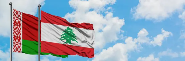 Bandera de Bielorrusia y Líbano ondeando en el viento contra el cielo azul nublado blanco juntos. Concepto diplomático, relaciones internacionales . — Foto de Stock