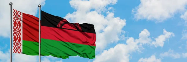 Bandera de Bielorrusia y Malawi ondeando en el viento contra el cielo azul nublado blanco juntos. Concepto diplomático, relaciones internacionales . — Foto de Stock