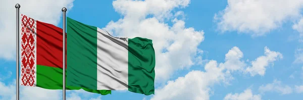 Bandera de Bielorrusia y Nigeria ondeando en el viento contra el cielo azul nublado blanco juntos. Concepto diplomático, relaciones internacionales . — Foto de Stock
