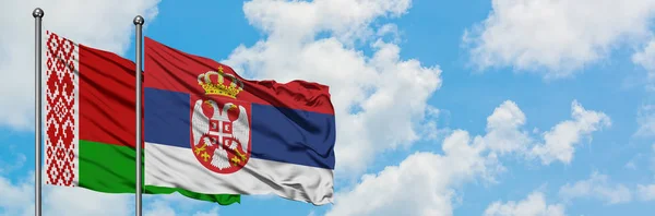 Bandera de Bielorrusia y Serbia ondeando en el viento contra el cielo azul nublado blanco juntos. Concepto diplomático, relaciones internacionales . — Foto de Stock