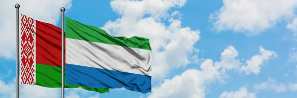 Bandera de Bielorrusia y Sierra Leona ondeando en el viento contra el cielo azul nublado blanco juntos. Concepto diplomático, relaciones internacionales . — Foto de Stock
