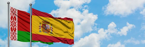 Bielorussia e Spagna bandiera sventolando nel vento contro bianco cielo blu nuvoloso insieme. Concetto di diplomazia, relazioni internazionali . — Foto Stock