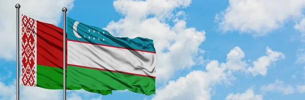Bandera de Bielorrusia y Uzbekistán ondeando en el viento contra el cielo azul nublado blanco juntos. Concepto diplomático, relaciones internacionales . —  Fotos de Stock