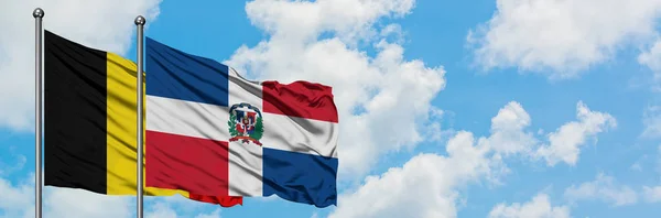 Bandera de Bélgica y República Dominicana ondeando en el viento contra el cielo azul nublado blanco juntos. Concepto diplomático, relaciones internacionales . — Foto de Stock
