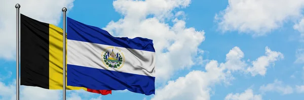 Belgien und El Salvador schwenken gemeinsam die Flagge im Wind vor dem wolkenverhangenen blauen Himmel. Diplomatie-Konzept, internationale Beziehungen. — Stockfoto