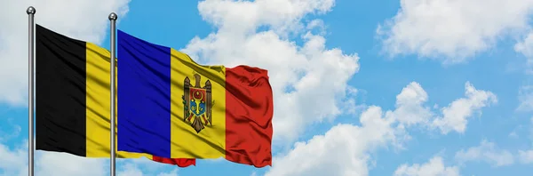 Die belgische und die moldawische Flagge wehen gemeinsam im Wind vor dem wolkenverhangenen blauen Himmel. Diplomatie-Konzept, internationale Beziehungen. — Stockfoto