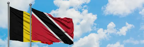 Belçika ve Trinidad ve Tobago bayrağı birlikte beyaz bulutlu mavi gökyüzüne karşı rüzgarda sallayarak. Diplomasi kavramı, uluslararası ilişkiler. — Stok fotoğraf