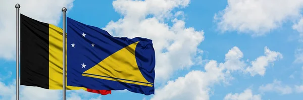 Bandera de Bélgica y Tokelau ondeando en el viento contra el cielo azul nublado blanco juntos. Concepto diplomático, relaciones internacionales . — Foto de Stock