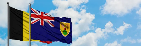 比利时和特克斯和凯科斯群岛的国旗在风中飘扬，与白云相间的蓝天相拥。外交概念、国际关系. — 图库照片