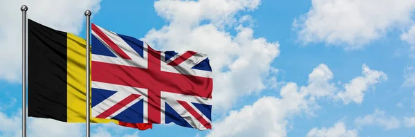 Belgio e Regno Unito bandiera sventolando nel vento contro bianco cielo blu nuvoloso insieme. Concetto di diplomazia, relazioni internazionali . — Foto Stock
