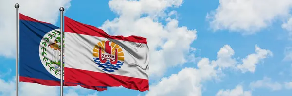 Беліз і Французька Полінезія прапор розмахуючи в вітру проти білого хмарного синього неба разом. Концепція дипломатії, міжнародні відносини. — стокове фото