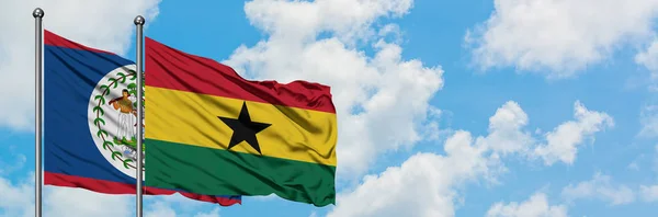 Bandera de Belice y Ghana ondeando en el viento contra el cielo azul nublado blanco juntos. Concepto diplomático, relaciones internacionales . — Foto de Stock