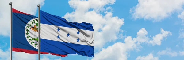 Belize en Honduras vlag zwaaien in de wind tegen witte bewolkte blauwe hemel samen. Diplomatie concept, internationale betrekkingen. — Stockfoto