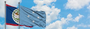 Belize ve Mikronezya bayrağı birlikte beyaz bulutlu mavi gökyüzüne karşı rüzgarda sallayarak. Diplomasi kavramı, uluslararası ilişkiler.