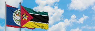 Belize ve Mozambik bayrağı birlikte beyaz bulutlu mavi gökyüzüne karşı rüzgarda sallayarak. Diplomasi kavramı, uluslararası ilişkiler.