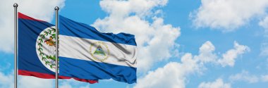 Belize ve Nikaragua bayrağı birlikte beyaz bulutlu mavi gökyüzüne karşı rüzgarda sallayarak. Diplomasi kavramı, uluslararası ilişkiler.