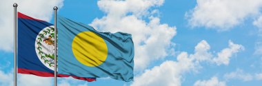 Belize ve Palau bayrağı birlikte beyaz bulutlu mavi gökyüzüne karşı rüzgarda sallayarak. Diplomasi kavramı, uluslararası ilişkiler.