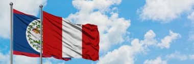 Belize ve Peru bayrağı birlikte beyaz bulutlu mavi gökyüzüne karşı rüzgarda sallayarak. Diplomasi kavramı, uluslararası ilişkiler.