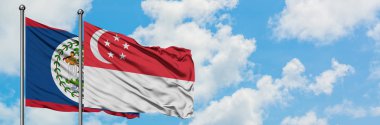 Belize ve Singapur bayrağı birlikte beyaz bulutlu mavi gökyüzüne karşı rüzgarda sallayarak. Diplomasi kavramı, uluslararası ilişkiler.