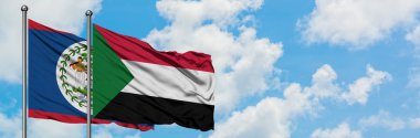 Belize ve Sudan bayrağı birlikte beyaz bulutlu mavi gökyüzüne karşı rüzgarda sallayarak. Diplomasi kavramı, uluslararası ilişkiler.