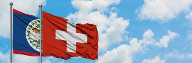Belize ve İsviçre bayrağı birlikte beyaz bulutlu mavi gökyüzüne karşı rüzgarda sallayarak. Diplomasi kavramı, uluslararası ilişkiler.