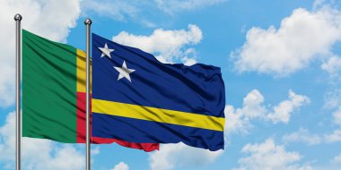 Benin ve Curacao bayrağı birlikte beyaz bulutlu mavi gökyüzüne karşı rüzgarda sallayarak. Diplomasi kavramı, uluslararası ilişkiler.