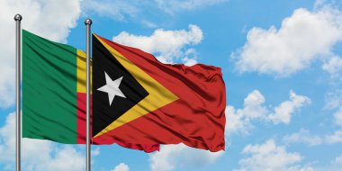 Benin ve Doğu Timor bayrağı birlikte beyaz bulutlu mavi gökyüzüne karşı rüzgarda sallayarak. Diplomasi kavramı, uluslararası ilişkiler.