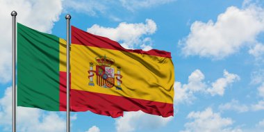 Benin ve İspanya bayrağı birlikte beyaz bulutlu mavi gökyüzüne karşı rüzgarda sallayarak. Diplomasi kavramı, uluslararası ilişkiler.