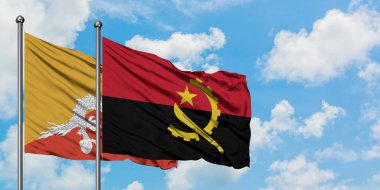 Bhutan ve Angola bayrağı birlikte beyaz bulutlu mavi gökyüzüne karşı rüzgarda sallayarak. Diplomasi kavramı, uluslararası ilişkiler.