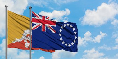 Bhutan ve Cook Adaları bayrağı birlikte beyaz bulutlu mavi gökyüzüne karşı rüzgarda sallayarak. Diplomasi kavramı, uluslararası ilişkiler.