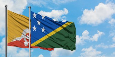 Bhutan ve Solomon Adaları bayrağı birlikte beyaz bulutlu mavi gökyüzüne karşı rüzgarda sallayarak. Diplomasi kavramı, uluslararası ilişkiler.