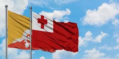Bhutan ve Tonga bayrağı birlikte beyaz bulutlu mavi gökyüzüne karşı rüzgarda sallayarak. Diplomasi kavramı, uluslararası ilişkiler.