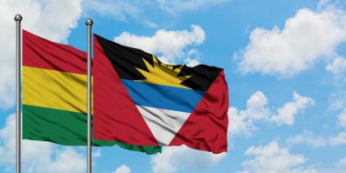 Bolivya ve Antigua ve Barbuda bayrağı birlikte beyaz bulutlu mavi gökyüzüne karşı rüzgarda sallayarak. Diplomasi kavramı, uluslararası ilişkiler.