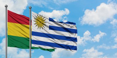 Bolivya ve Uruguay bayrağı birlikte beyaz bulutlu mavi gökyüzüne karşı rüzgarda sallayarak. Diplomasi kavramı, uluslararası ilişkiler.