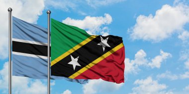Botsvana ve Saint Kitts ve Nevis bayrağı birlikte beyaz bulutlu mavi gökyüzüne karşı rüzgarda sallayarak. Diplomasi kavramı, uluslararası ilişkiler.