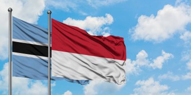 Botsvana ve Monako bayrağı birlikte beyaz bulutlu mavi gökyüzüne karşı rüzgarda sallayarak. Diplomasi kavramı, uluslararası ilişkiler.