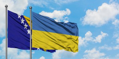 Bosna Hersek ve Ukrayna bayrağı birlikte beyaz bulutlu mavi gökyüzüne karşı rüzgarda sallayarak. Diplomasi kavramı, uluslararası ilişkiler.