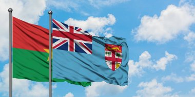 Burkina Faso ve Fiji bayrağı birlikte beyaz bulutlu mavi gökyüzüne karşı rüzgarda sallayarak. Diplomasi kavramı, uluslararası ilişkiler.