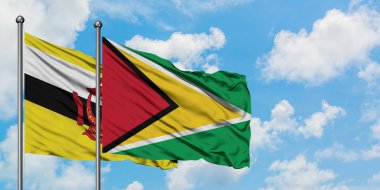 Brunei ve Guyana bayrağı birlikte beyaz bulutlu mavi gökyüzüne karşı rüzgarda sallayarak. Diplomasi kavramı, uluslararası ilişkiler.