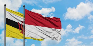 Brunei ve Monako bayrağı birlikte beyaz bulutlu mavi gökyüzüne karşı rüzgarda sallayarak. Diplomasi kavramı, uluslararası ilişkiler.