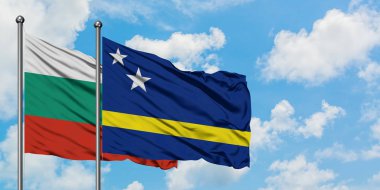 Bulgaristan ve Curacao bayrağı birlikte beyaz bulutlu mavi gökyüzüne karşı rüzgarda sallayarak. Diplomasi kavramı, uluslararası ilişkiler.