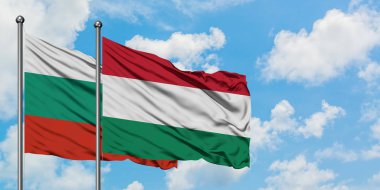 Bulgaristan ve Macaristan bayrağı birlikte beyaz bulutlu mavi gökyüzüne karşı rüzgarda sallayarak. Diplomasi kavramı, uluslararası ilişkiler.