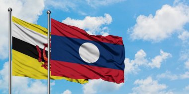 Brunei ve Laos bayrağı birlikte beyaz bulutlu mavi gökyüzüne karşı rüzgarda sallayarak. Diplomasi kavramı, uluslararası ilişkiler.