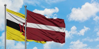 Brunei ve Letonya bayrağı birlikte beyaz bulutlu mavi gökyüzüne karşı rüzgarda sallayarak. Diplomasi kavramı, uluslararası ilişkiler.