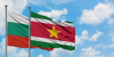 Bulgaristan ve Surinam bayrağı birlikte beyaz bulutlu mavi gökyüzüne karşı rüzgarsal sallayarak. Diplomasi kavramı, uluslararası ilişkiler.