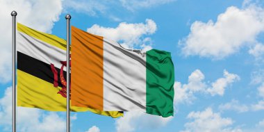 Brunei ve Fildişi Sahili bayrağı birlikte beyaz bulutlu mavi gökyüzüne karşı rüzgarda sallayarak. Diplomasi kavramı, uluslararası ilişkiler.