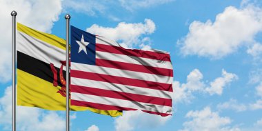 Brunei ve Liberya bayrağı birlikte beyaz bulutlu mavi gökyüzüne karşı rüzgarda sallayarak. Diplomasi kavramı, uluslararası ilişkiler.