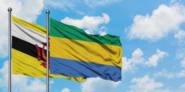 Brunei ve Gabon bayrağı birlikte beyaz bulutlu mavi gökyüzüne karşı rüzgarda sallayarak. Diplomasi kavramı, uluslararası ilişkiler.