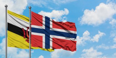 Brunei ve Norveç bayrağı birlikte beyaz bulutlu mavi gökyüzüne karşı rüzgarda sallayarak. Diplomasi kavramı, uluslararası ilişkiler.