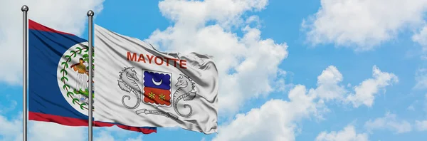 Belize e bandeira Mayotte acenando no vento contra o céu azul nublado branco juntos. Conceito de diplomacia, relações internacionais . — Fotografia de Stock